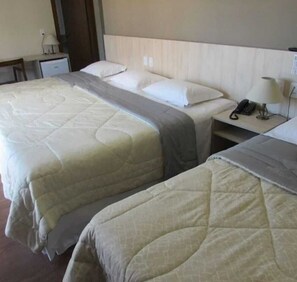 Une chambre d’hôtel avec deux lits, une table de chevet avec une lampe et un téléphone.