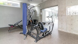 Uma academia com equipamentos de exercícios, um pilar azul e uma janela.