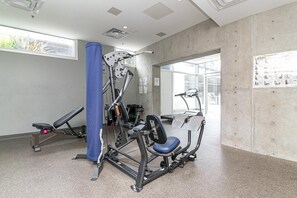 Ein Fitnessstudio mit Trainingsgeräten, einer blauen Säule und einem Fenster.