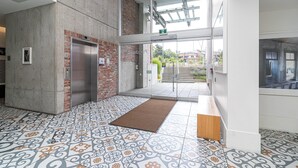Um interior com piso estampado, parede de concreto e porta de vidro que dá para o exterior.