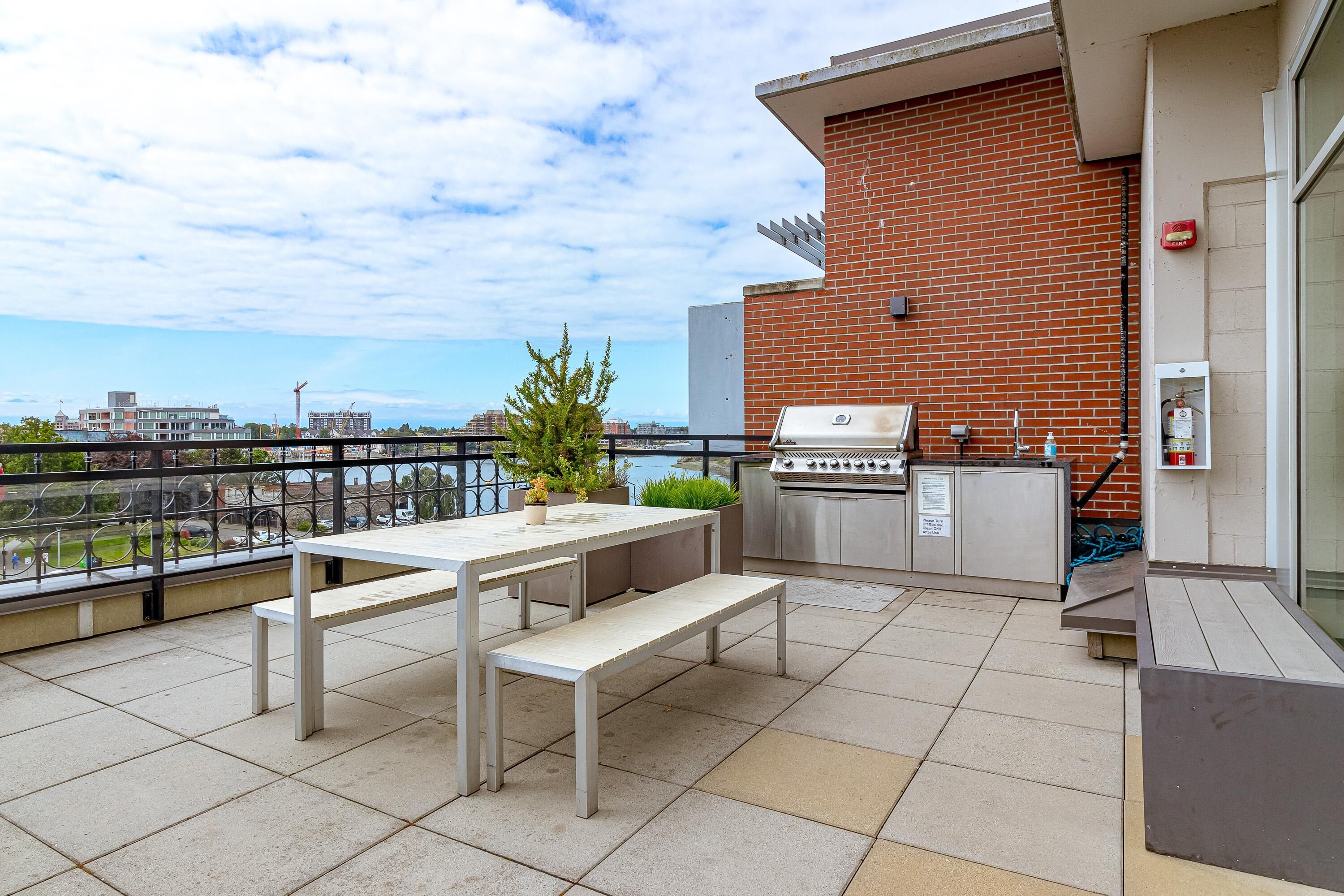 Eine Terrasse im Freien mit Grill, Sitzgelegenheiten und Blick auf die Stadt.