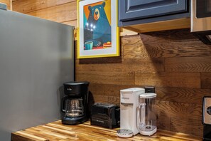 A kitchen with a coffee maker, a water dispenser, and a framed picture on the wall. - Renovated Playhouse—Slide/Views/Fire Pit/Hot Tub (Pigeon Forge)