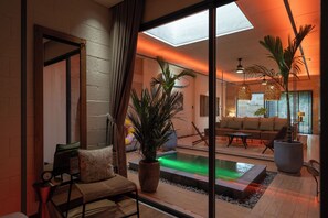 A modern interior with a pool, seating area, and large windows. - Mui Ne Beachside Private Villa (Mũi Né)