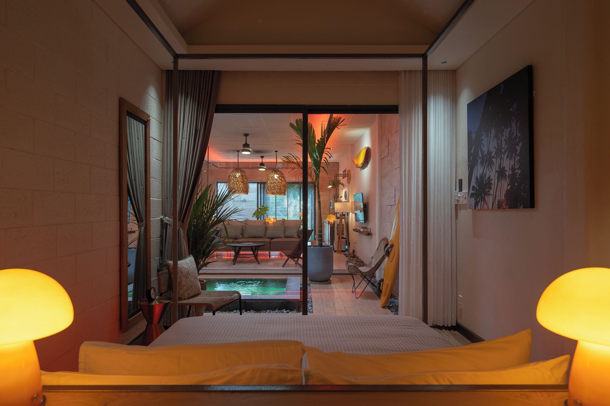 A hotel room with a bed, a sofa, a small table, a lamp, a TV, and a view of the outside.
