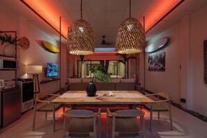 A dining area with a long table, chairs, a vase, and a television on a stand. - Mui Ne Beachside Private Villa (Mũi Né)