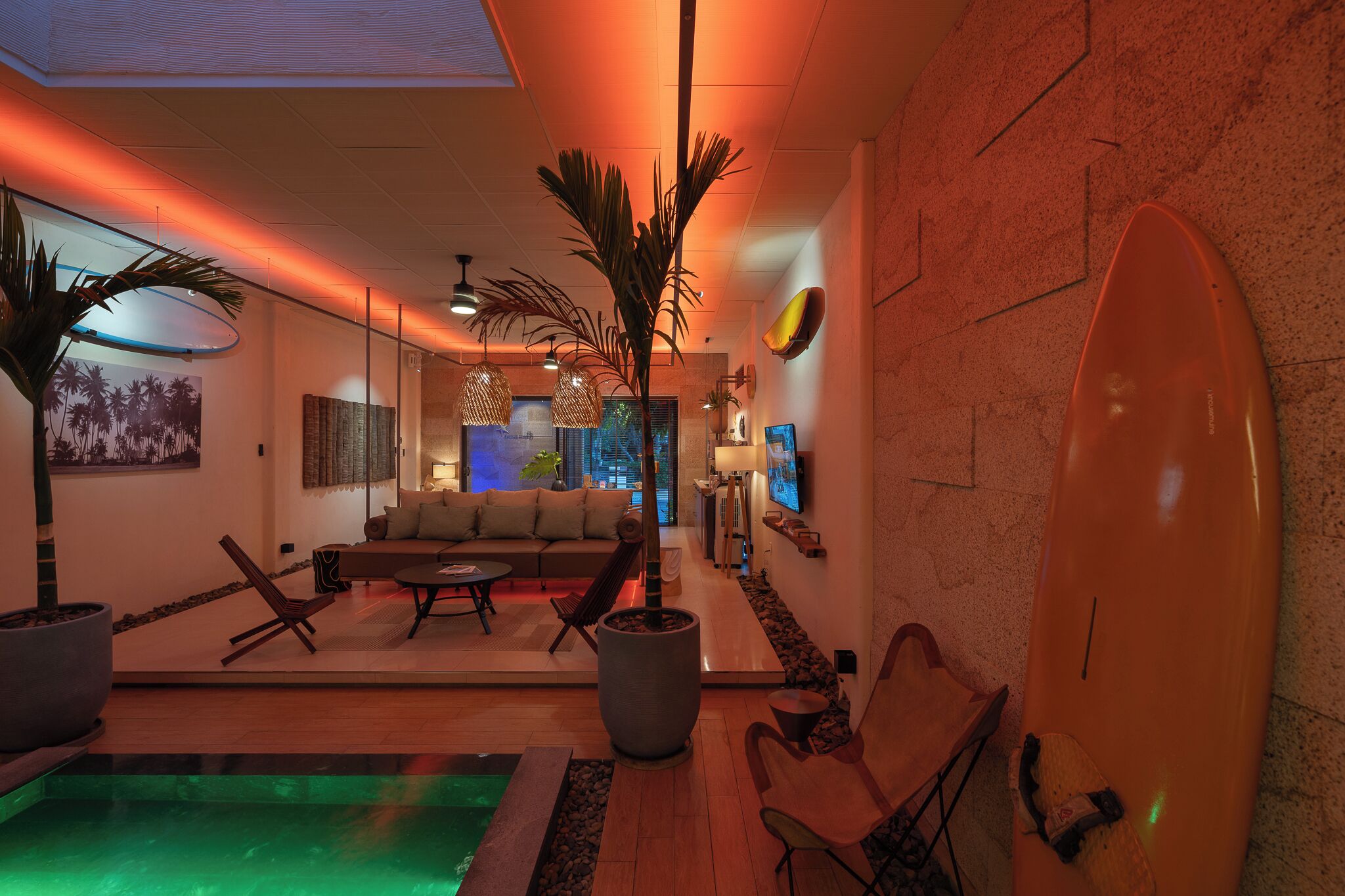 A modern interior with a pool, seating area, and a surfboard decoration.
