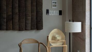 A room with a wooden chair, a woven basket, and a blue bag on the floor.