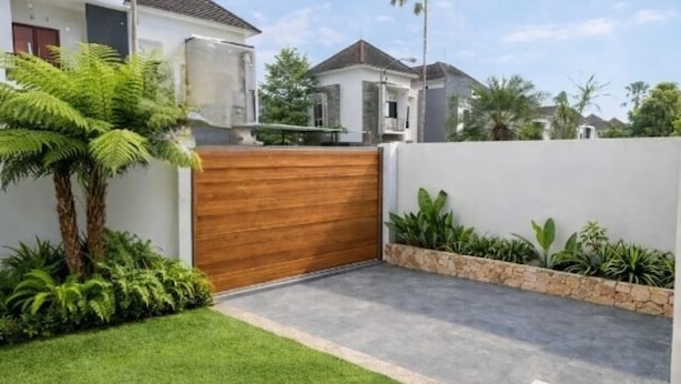 A residential property with a wooden gate, a well-maintained lawn, and a stone wall.