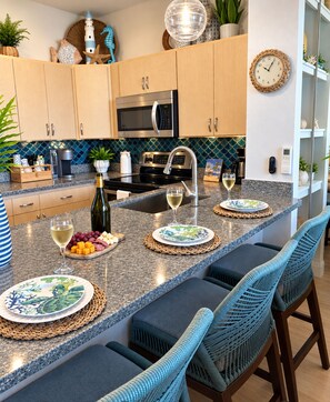 A modern kitchen with a central island, stainless steel appliances, and a decorative backsplash. - Oceanfront, swim with turtles, enjoy sunset views, all from your backyard. #B18 (Lahaina)