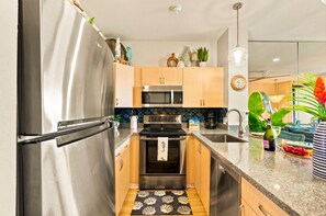 A modern kitchen with stainless steel appliances, wooden cabinets, and a granite countertop. - Oceanfront, swim with turtles, enjoy sunset views, all from your backyard. #B18 (Lahaina)