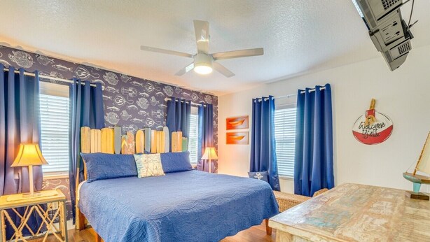 A bedroom with a bed, a ceiling fan, a desk, and a wall-mounted projector. - Homosassa Riverfront Stay with Private Dock (Homosassa)