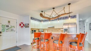 A kitchen with a bar area, wooden chairs, and a unique ceiling light fixture. - Homosassa Riverfront Stay with Private Dock (Homosassa)