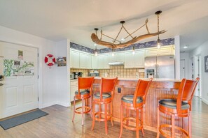 A kitchen with a bar area, wooden chairs, and a unique ceiling light fixture. - Homosassa Riverfront Stay with Private Dock (Homosassa)