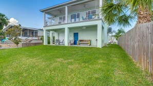 A two-story house with a covered patio, a blue door, and a wooden fence. - Homosassa Riverfront Stay with Private Dock (Homosassa)