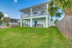 A two-story house with a covered patio, a blue door, and a wooden fence. - Homosassa Riverfront Stay with Private Dock (Homosassa)