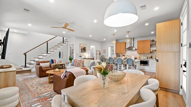 A modern kitchen with wooden cabinets, a dining area with a wooden table and chairs, and a staircase leading to another level. - Hidden Haven | 5 mins to Folly, Luxury New Build (Charleston)