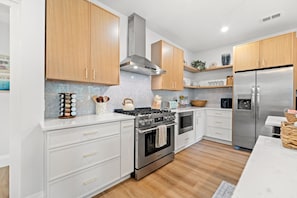 Eine moderne Küche mit Edelstahlgeräten, Holzschränken und einer Marmor-Spritzschutzwand.