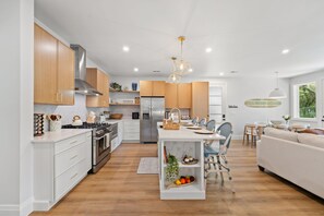 A modern kitchen with white cabinetry, stainless steel appliances, and a central island with seating. - Hidden Haven | 5 mins to Folly, Luxury New Build (Charleston)