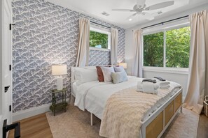 A bedroom with a bed, bedside lamps, a window with curtains, and a ceiling fan. - Hidden Haven | 5 mins to Folly, Luxury New Build (Charleston)