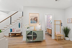 Ein modernes Interieur mit einer Treppe, einem grünen Konsolentisch mit Glastüren, einer gerahmten Zeitung und einer Wand mit einem gemusterten Vorhang.