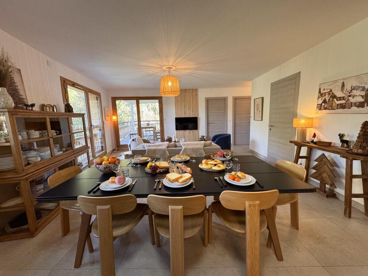 A dining area with a long table set for a meal, surrounded by wooden chairs.