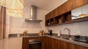 Una cucina moderna con mobili in legno, una cappa aspirante in acciaio inossidabile, un forno integrato, un lavello con rubinetto e una macchina da caffè.