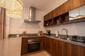 Eine moderne Küche mit Holzschränken, einer Edelstahl-Dunstabzugshaube, einem Backofen, einem Spülbecken mit Armatur und einer Kaffeemaschine.