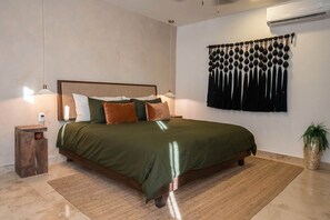 Ein ordentlich eingerichtetes Schlafzimmer mit einem Bett, Nachttischen, einer Wand-Klimaanlage und einer Wandtasche.