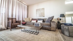 Un salon comprenant un canapé, des fauteuils, une table basse et un élément décoratif mural.