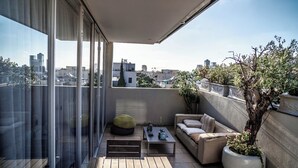 Un balcon avec un canapé, une table et un pot de fleurs.