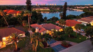 Un barrio residencial con casas, un lago y el horizonte de una ciudad al fondo.
