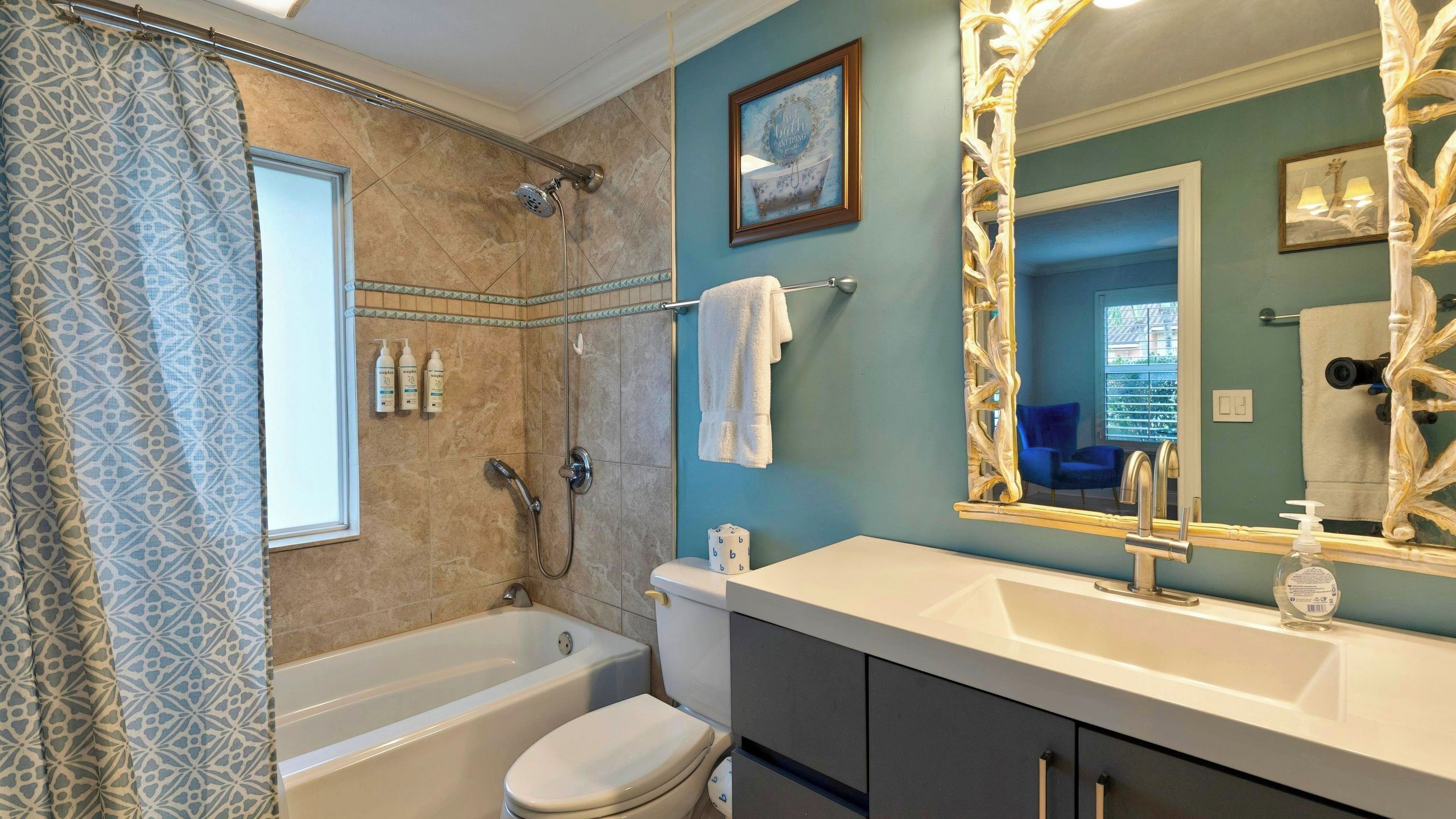 A bathroom with a bathtub, toilet, vanity with a large mirror, and a shower.