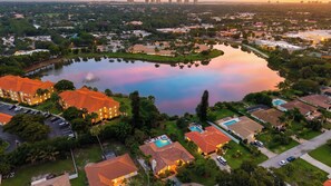 Zona residencial con una gran masa de agua, casas de techo rojo y una piscina.