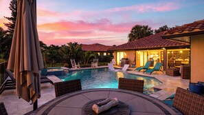 A pool area with lounge chairs, a hot tub, and a patio with a table and chairs. - Blue Sunset by Avantstay Pool + Spa + Fire Table Near Beaches + Naples (Bonita Springs)