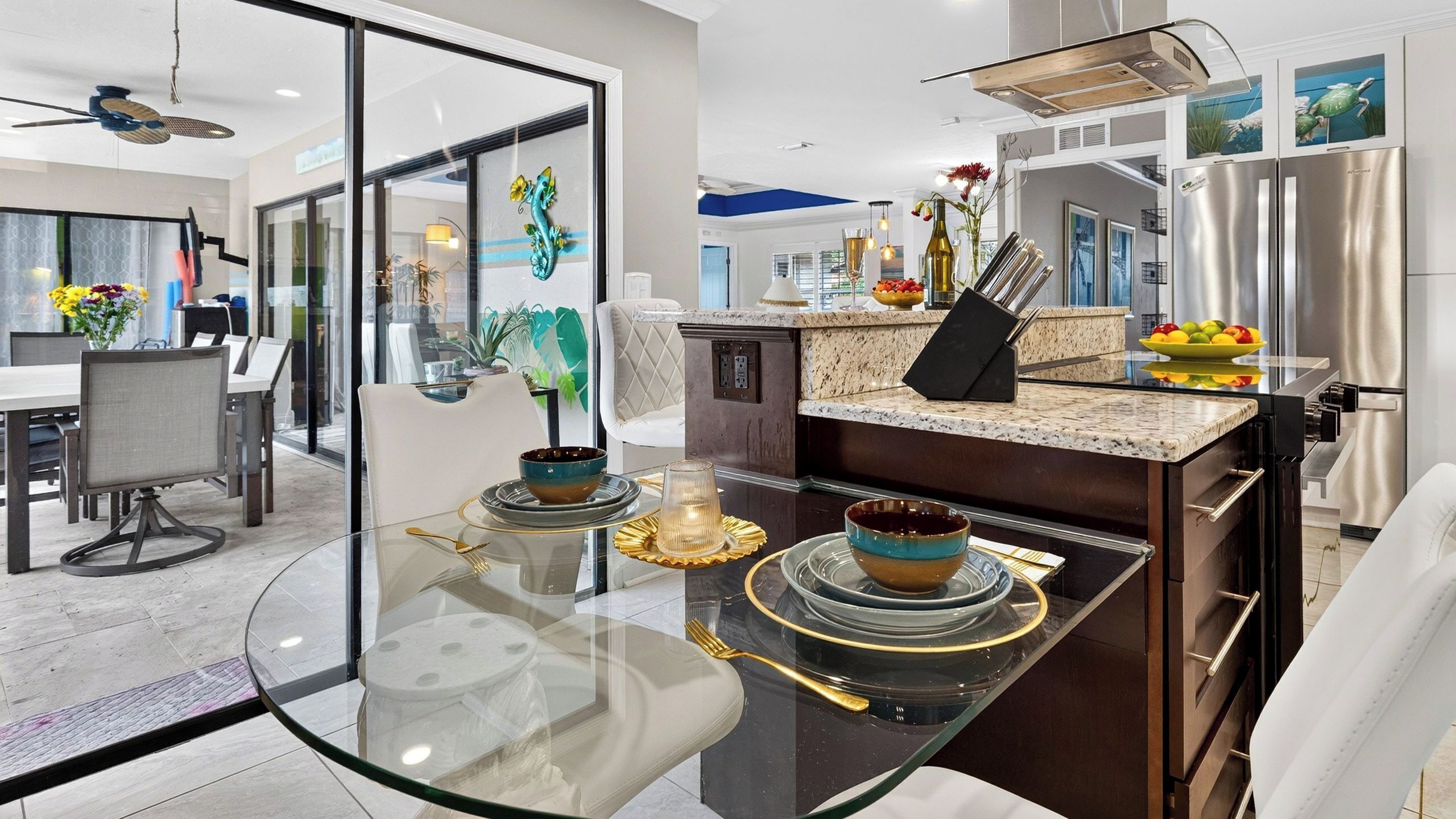 A modern kitchen with a glass dining table, stainless steel appliances, and a view into the dining area.