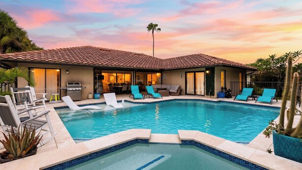 Un área de piscina con jacuzzi, sillas de descanso y una parrilla.