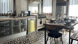 Uma cozinha com uma ilha central, fogão e mesa de jantar com cadeiras.
