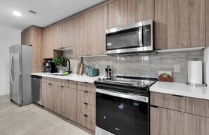 Eine moderne Küche mit Holzschränken, Edelstahlgeräten und einer Marmor-Spritzschutzwand.
