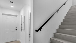 A staircase with a black handrail, a white door, and a light-colored floor. - El Mirador (Homestead)