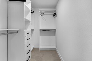 Ein begehbarer Kleiderschrank mit offenen Regalen, einer Kleiderstange und Schubladen.
