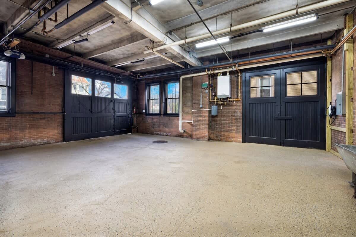 Een ruime kamer in industriële stijl, met zichtbare bakstenen muren, grote zwarte deuren en open riolering.