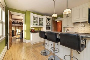 A kitchen with a bar area, white cabinets, and a cityscape artwork. - 5BR Luxury Retreat With Huge Garage & 3 King Beds! (Milwaukee)