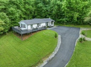 A single-story house with a covered porch, surrounded by a well-maintained lawn and a curved driveway.