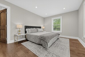 A bedroom with a bed, bedside tables, a window with blinds, and a door. - Luxe Highlands Hot Tub Retreat w Fire Pit! (Highlands)