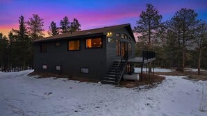 Eine moderne Holzhütte mit Treppe zu einer Terrasse, umgeben von Schnee.