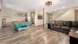 Ein Zimmer mit Billardtisch, einer Couch und einer Treppe.