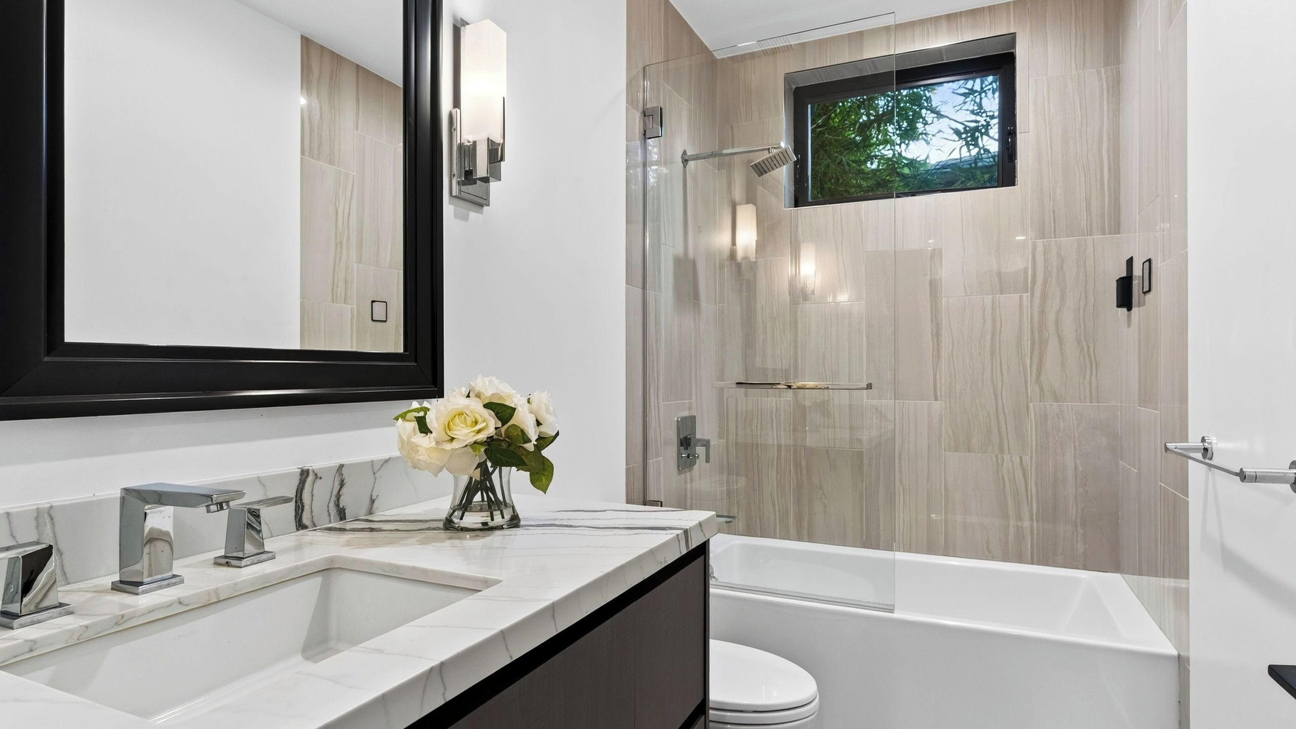 Une salle de bain moderne avec un grand miroir, une baignoire et une douche.