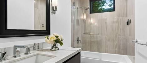 Une salle de bain moderne avec un grand miroir, une baignoire et une douche.