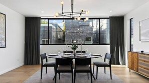 Ein moderner Essraum mit einem runden Tisch, schwarzen Stühlen und einer Chandelier.