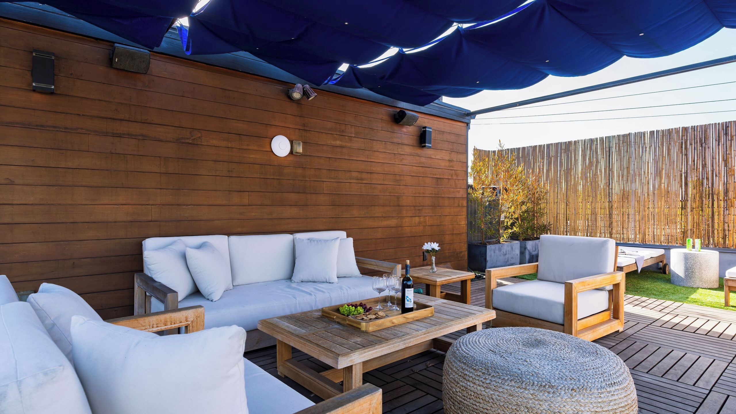 A wooden deck with a sofa, chairs, and a table set up for outdoor dining.